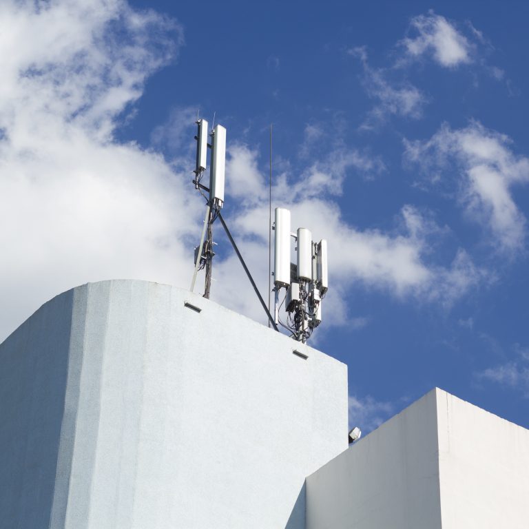 Smart cellular network antenna base station on the telecommunication mast on the roof of a building.