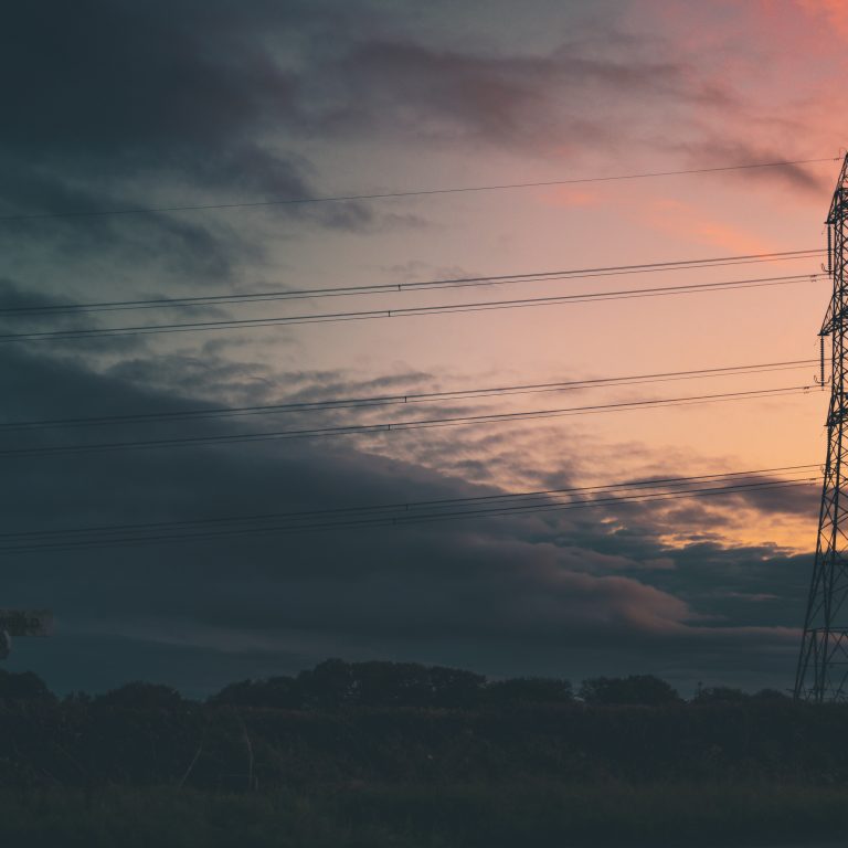 Silhouette of a transmission Tower - Power Pylon - Against a bright orange sunset