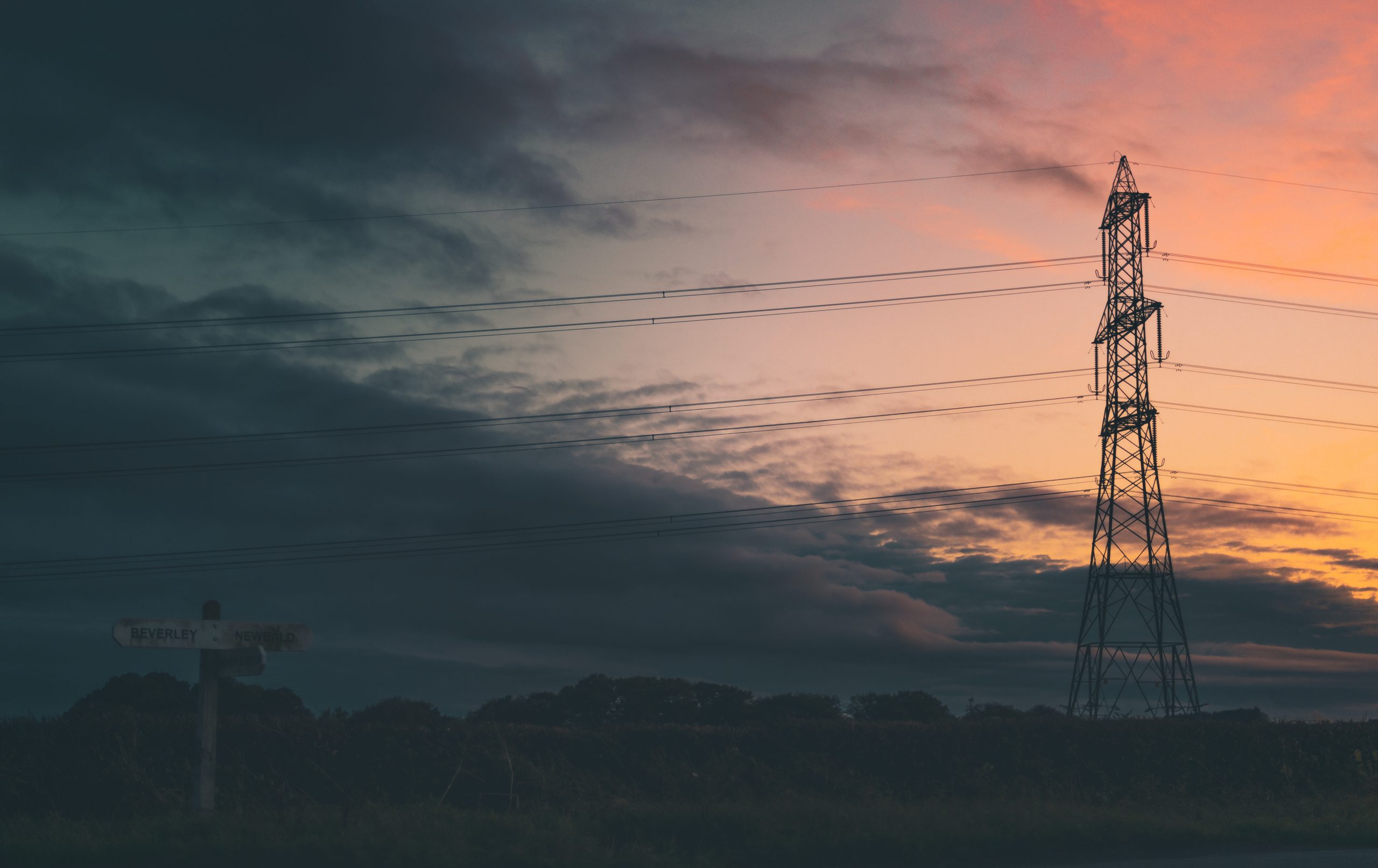 Silhouette of a transmission Tower - Power Pylon - Against a bright orange sunset