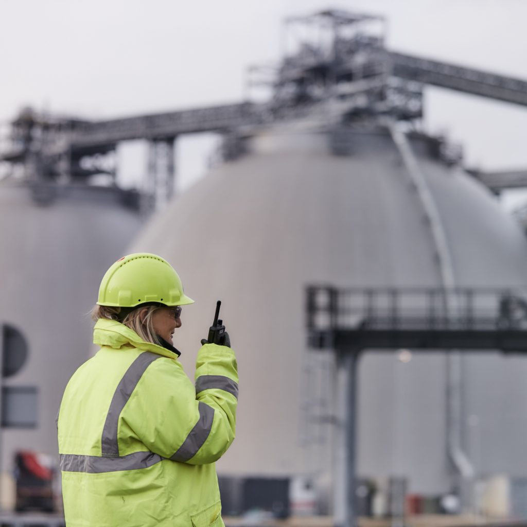 Drax employee in PPE in front of biomass storage dome