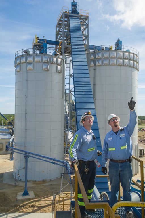 Engineers in front of wood pellet storage silos at Drax's Morehouse BioEnergy biomass manufacturing facility in northern Louisiana