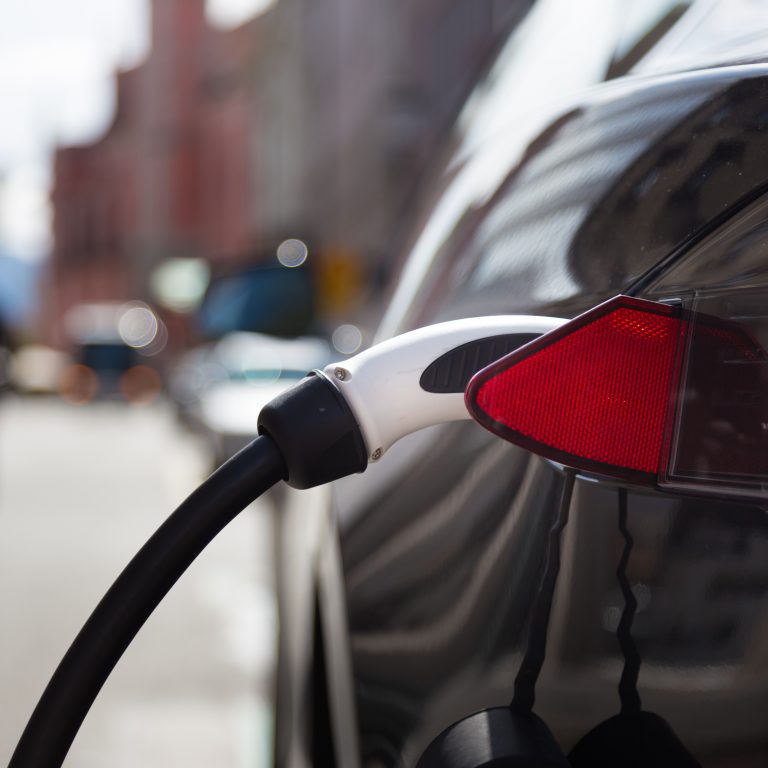 Power supply for electric car charging. Electric car charging station. Close up of the power supply plugged into an electric car being charged.