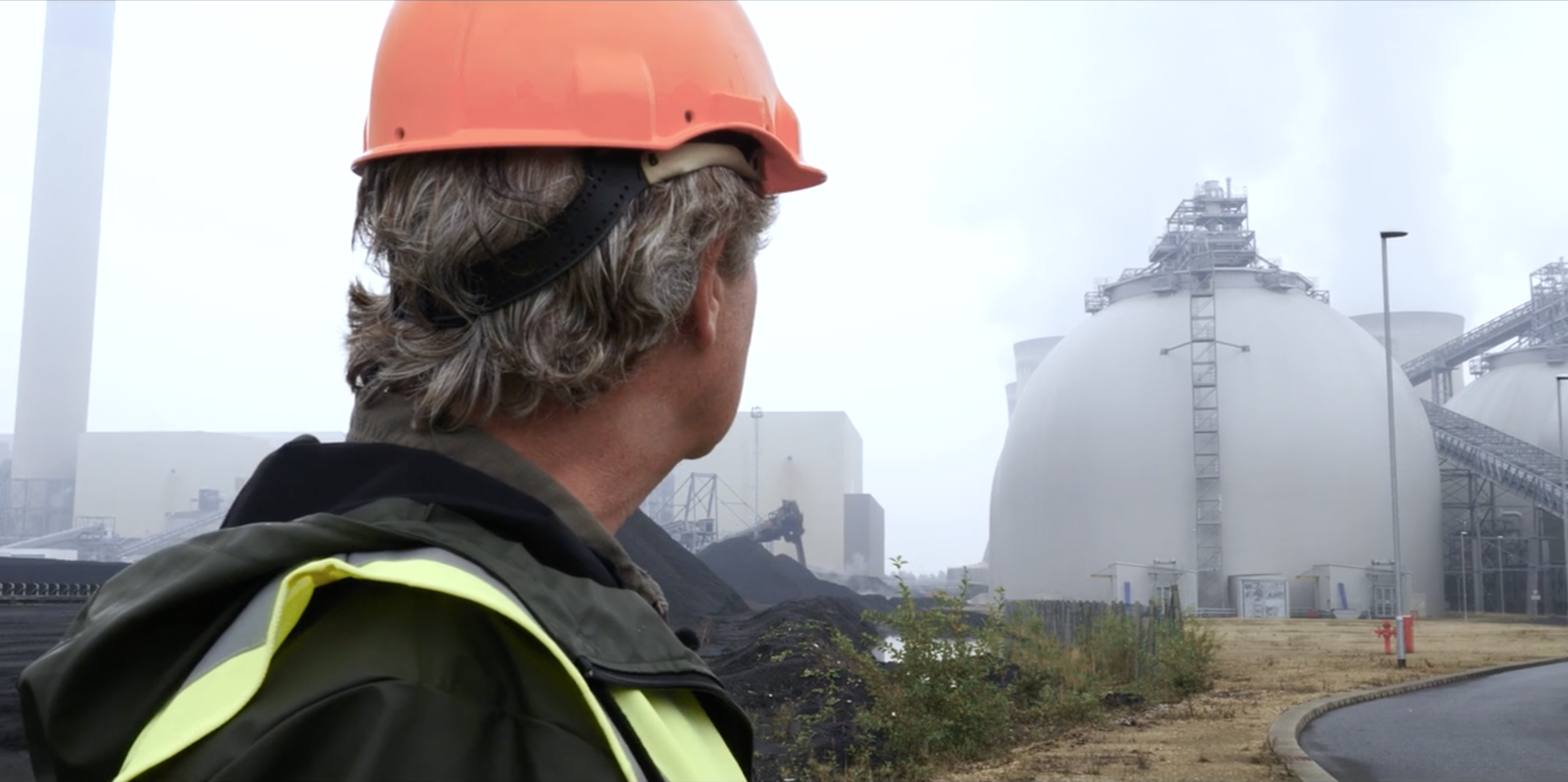 Tony Juniper at Drax Power Station between coal stock and biomass wood pellet storage domes