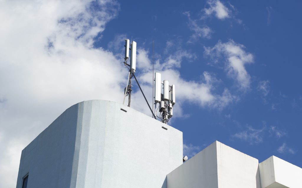 Smart cellular network antenna base station on the telecommunication mast on the roof of a building.