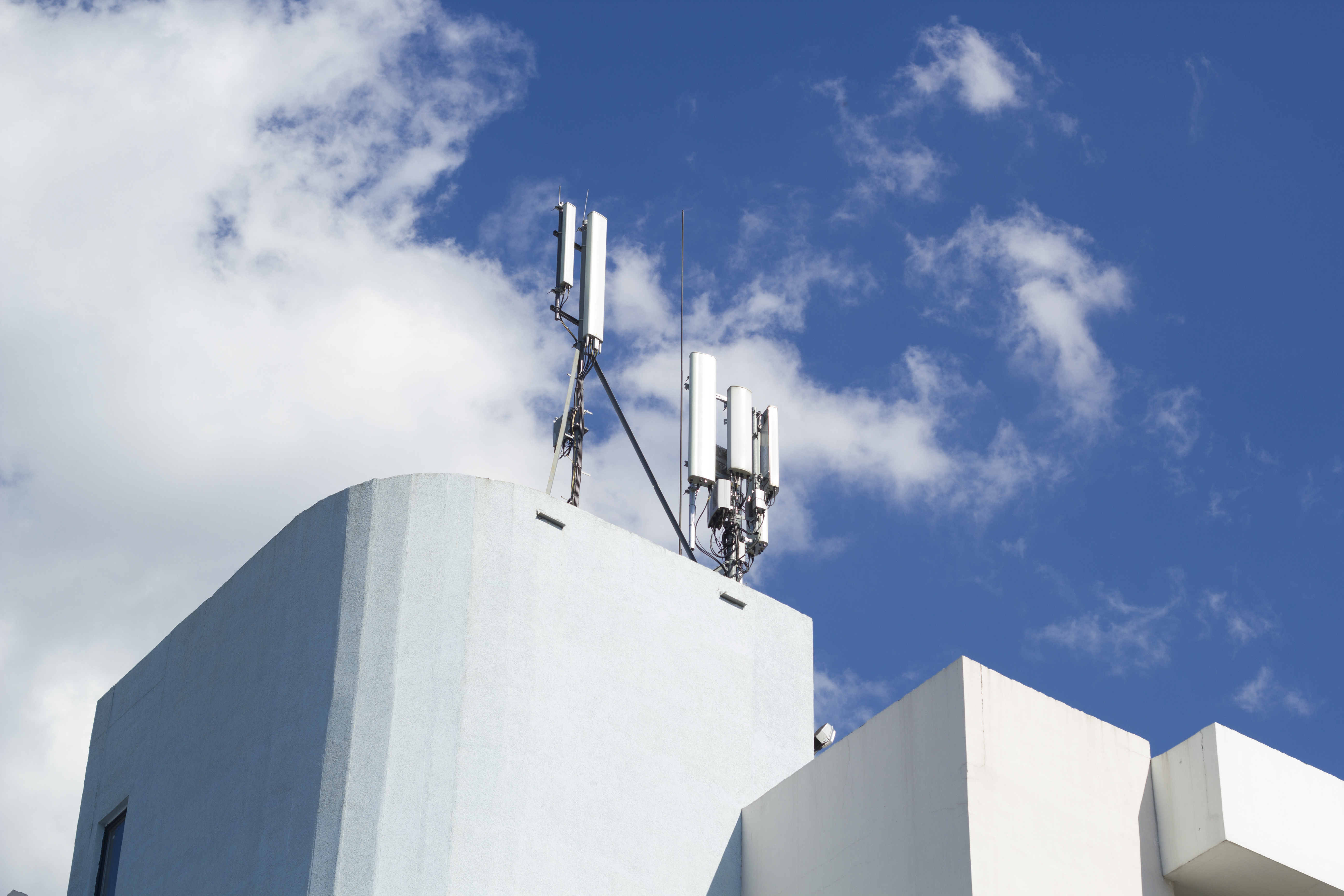 Smart cellular network antenna base station on the telecommunication mast on the roof of a building.