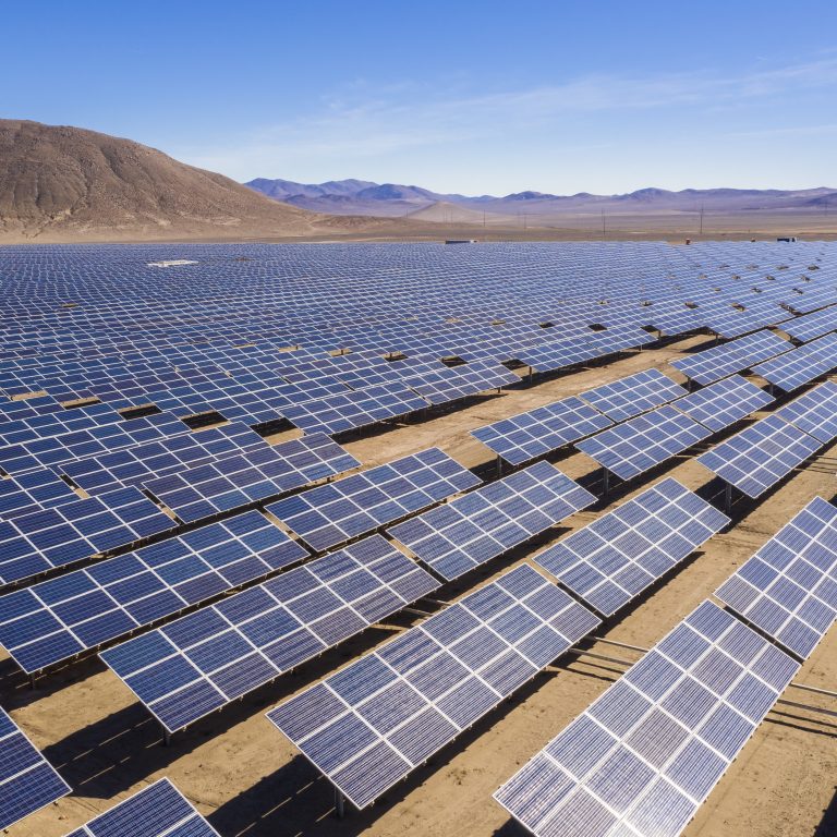 Aerial view of hundreds solar energy modules or panels rows along the dry lands at Atacama Desert, Chile. Huge Photovoltaic PV Plant in the middle of the desert from an aerial drone point of view