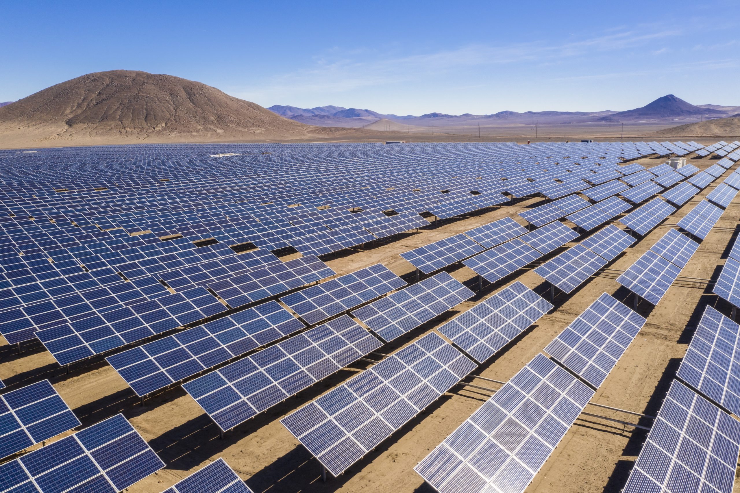 Aerial view of hundreds solar energy modules or panels rows along the dry lands at Atacama Desert, Chile. Huge Photovoltaic PV Plant in the middle of the desert from an aerial drone point of view