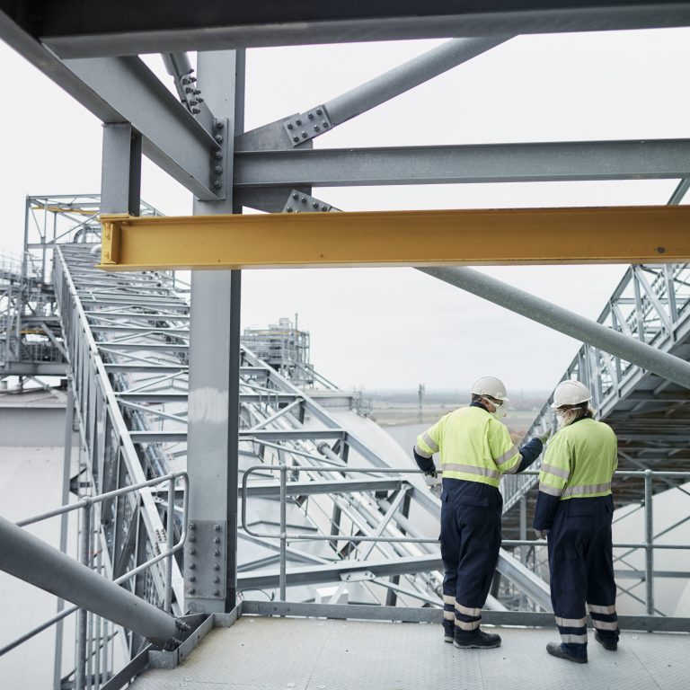 Engineers in PPE high above Drax Power Station looking towards biomass wood pellet storage dome