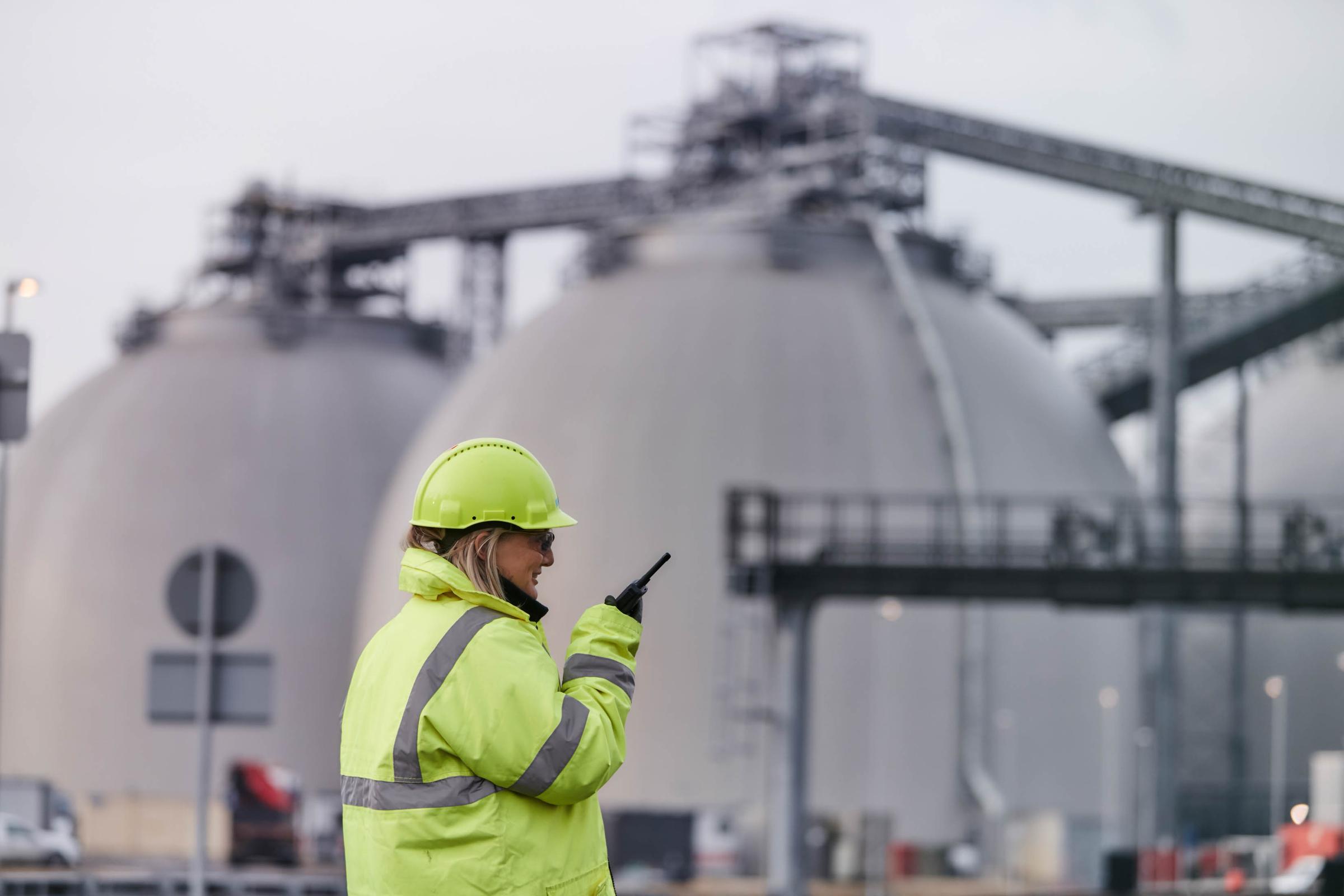 Drax Power Station biomass storage domes with employee in foreground wearing PPE