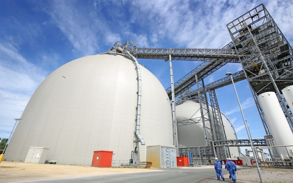 Engineers walking in front of sustainable biomass wood pellet storage dome at Drax Power Station, June 2021