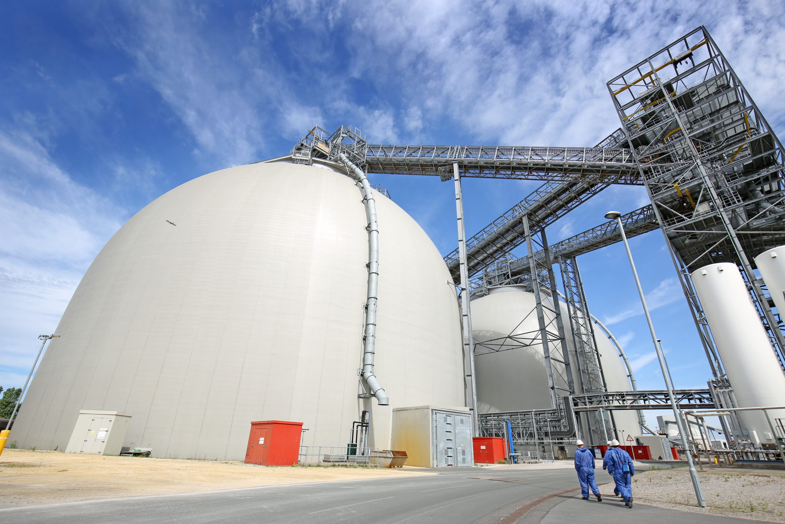 Engineers walking in front of sustainable biomass wood pellet storage dome at Drax Power Station, June 2021