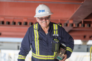 Drax worker in PPE walking around a pellet plant, holding a controller