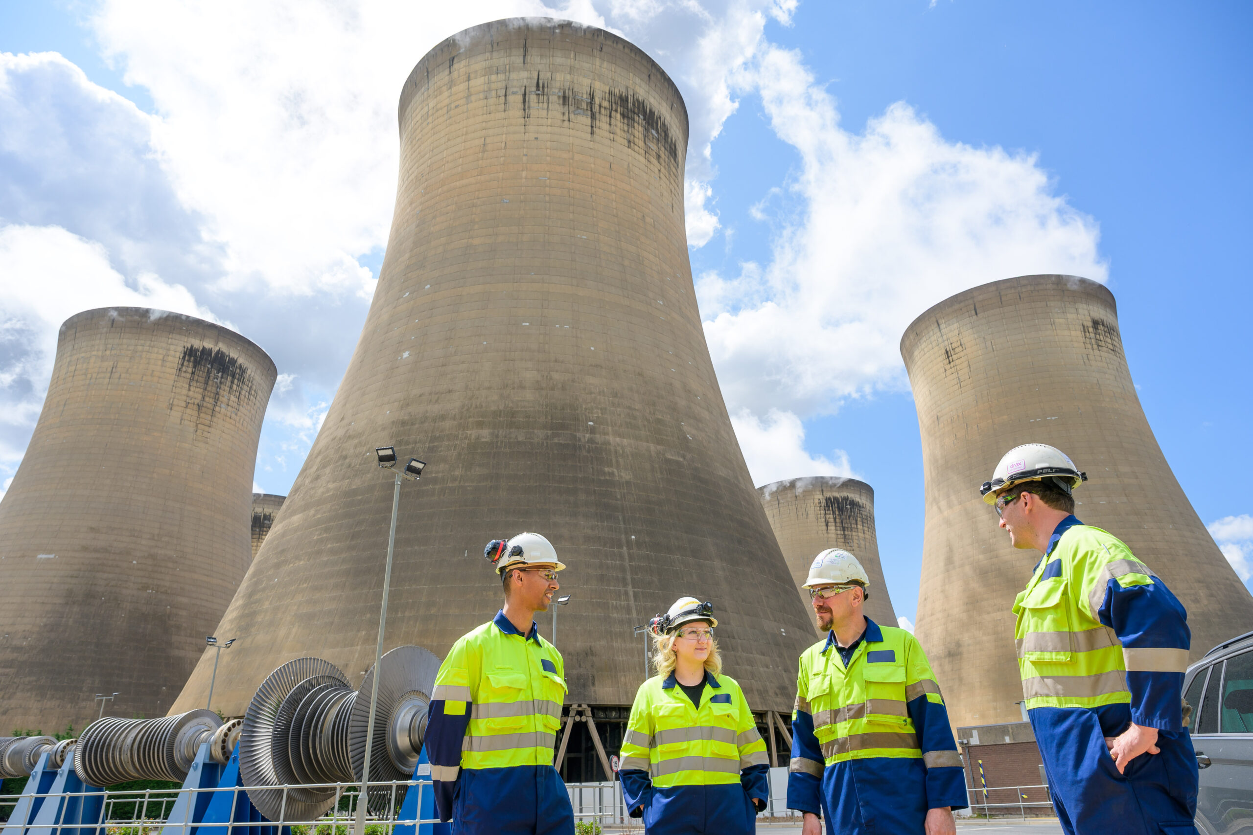 Drax workers in PPE speaking in front of cooling towers